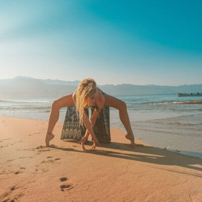woman practicing yoga on the beach - best yoga retreats in Mexico