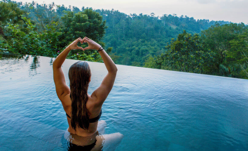 luxury yoga retreats - woman practicing yoga in an infinity pool