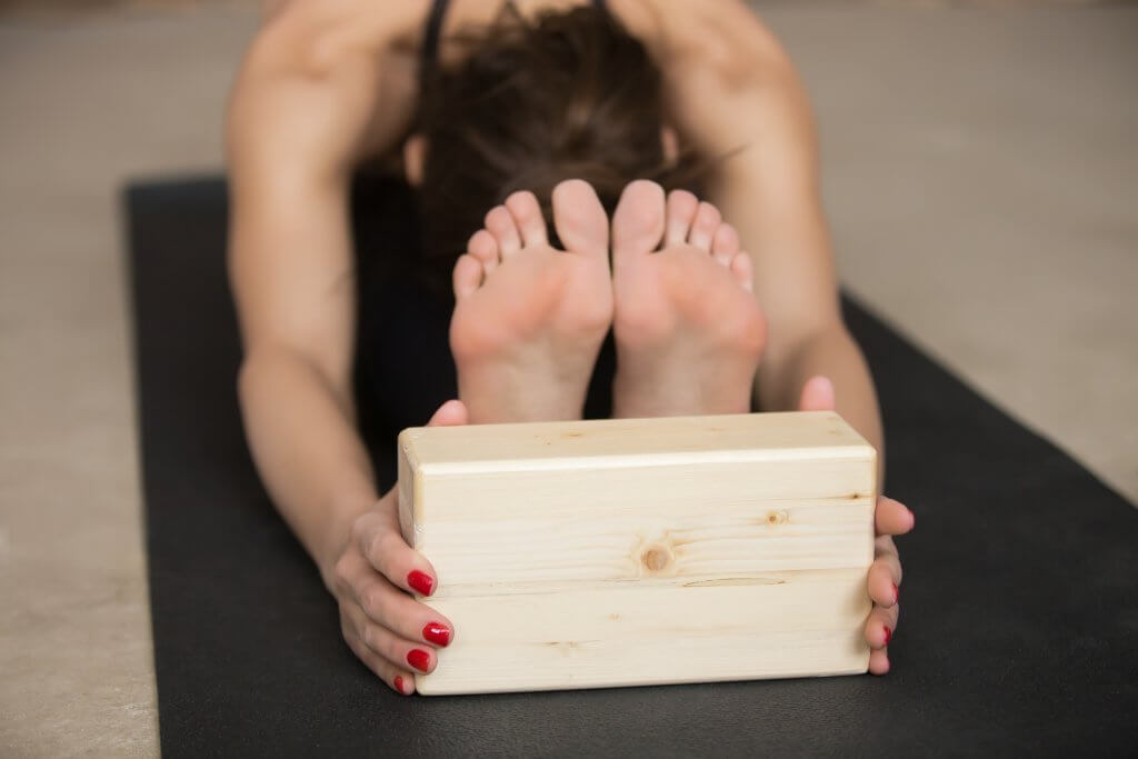 woman practicing yoga with a yoga block - best yoga blocks for beginners