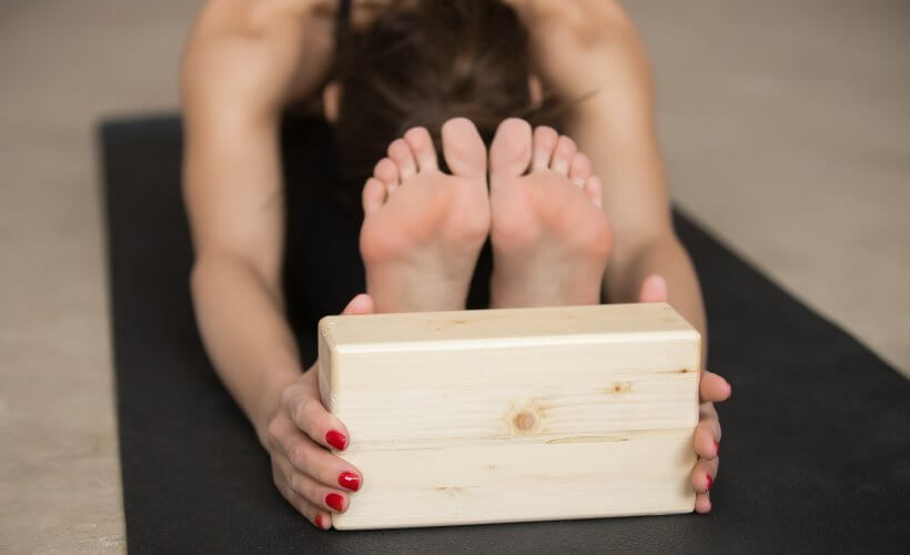 woman practicing yoga with a yoga block - best yoga blocks for beginners