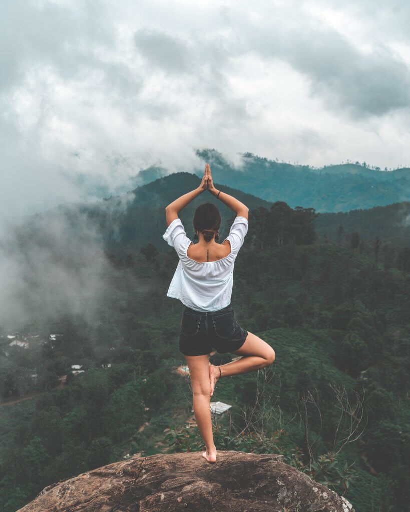 Woman doing yoga on a mountain - organic yoga clothing