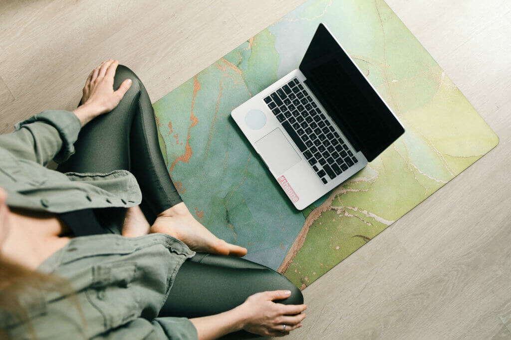 woman sitting cross-legged in front of computer - best online yoga teacher training