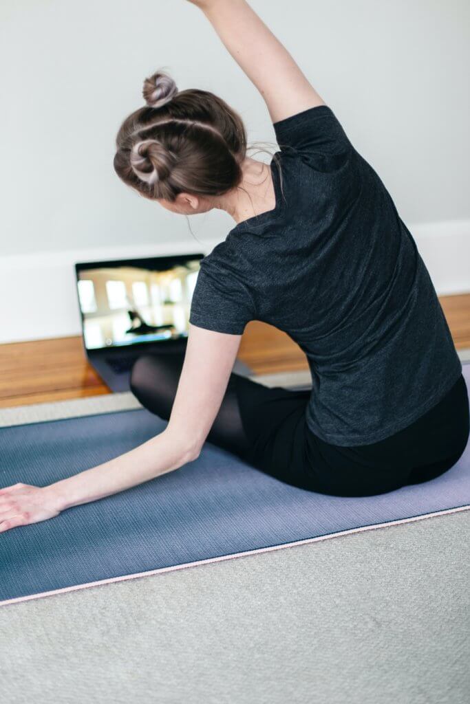 young woman doing yoga in front of computer