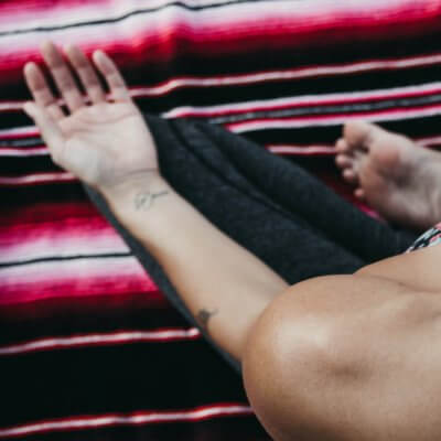 woman cross-legged seated on Mexican yoga blanket