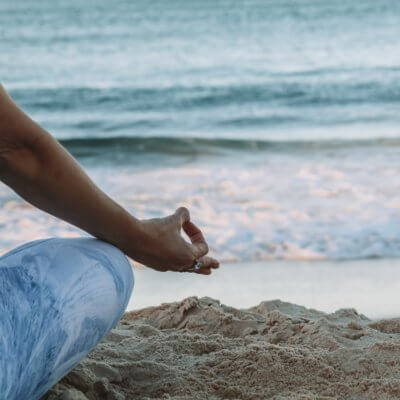 woman meditating on the beach - best yoga retreats in Europe