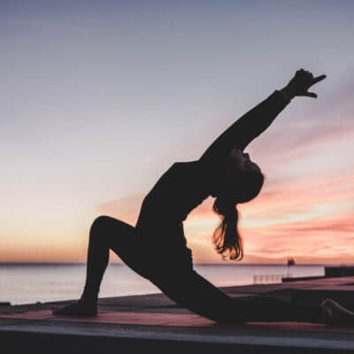 Woman doing yoga by the ocean - best yoga retreats in Portugal