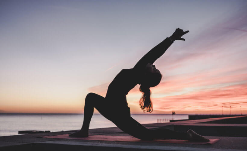 Woman doing yoga by the ocean - best yoga retreats in Portugal
