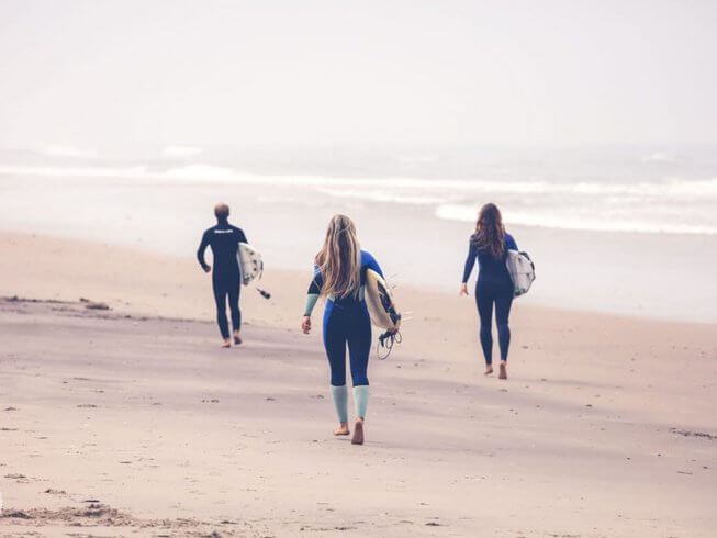 surfers walking on a beach - surf and yoga retreat in Portugal
