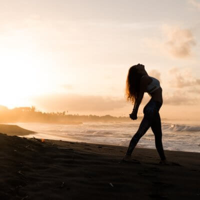 woman practicing yoga on the beach - best yoga retreats in Bali