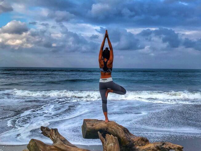 woman practicing yoga on the beach - best yoga retreats in Canggu, Bali