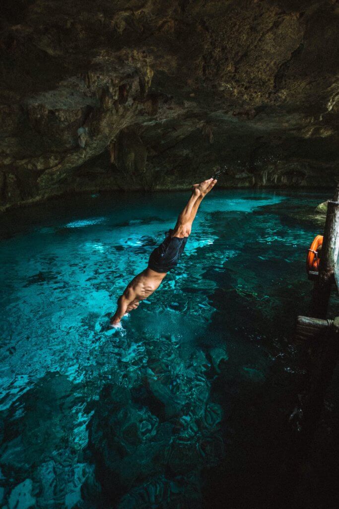 man diving into a cenote - Tulum yoga retreats